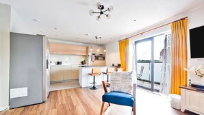 A modern apartment with a kitchen, dining area, and a balcony with yellow curtains.