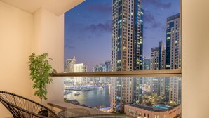 Een balkon met uitzicht op een stadsgezicht in de nacht, met wolkenkrabbers en een jachthaven.