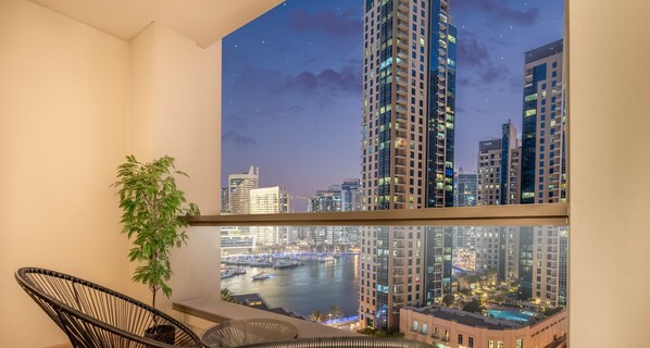 Varanda com vista para o horizonte urbano à noite, incluindo edifícios altos e um porto de iates.