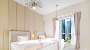 Een moderne hotelkamer met een groot bed, twee nachtkastjes, een hanglamp en uitzicht op hoge gebouwen door het raam.