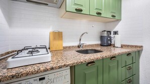 Una cocina funcional con estufa a gas, un lavamanos y una cafetera.