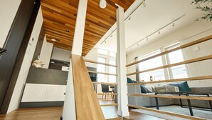 Ein modernes Interieur mit einer Holztreppe, einem grauen Sofa und einer Küche im Hintergrund.