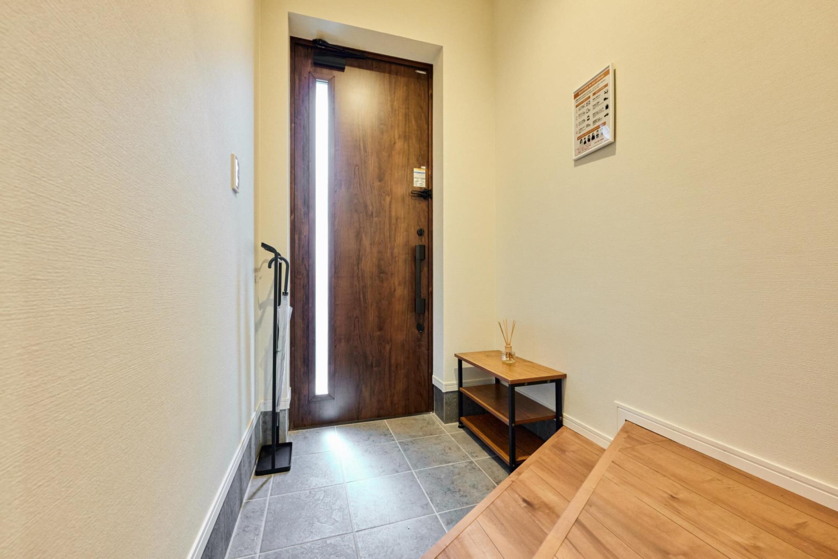 Un pasillo con una puerta de madera, una pequeña mesa con una vela y un cartel en la pared.