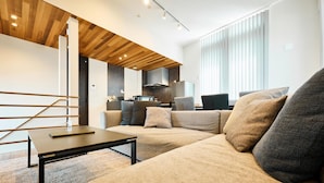 Ein modernes Wohnzimmer mit einem Ecksofa, einem Couchtisch und einer Treppe.