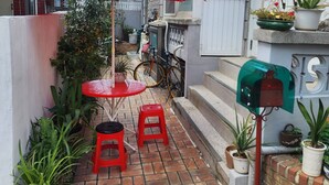 A small outdoor patio with a red umbrella, two red stools, and potted plants. - Disco PangPang GuestHouse (Foreigners only) (Incheon)