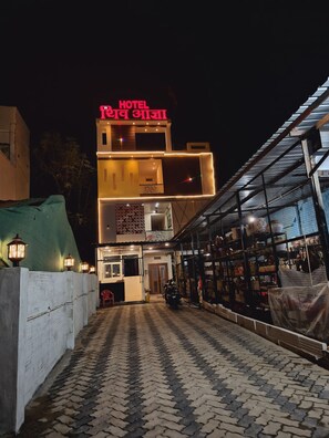 A hotel with a prominent sign, a covered outdoor area, and a motorcycle parked outside.