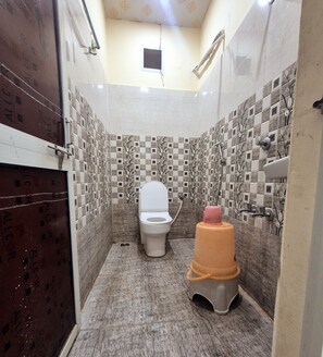 A bathroom with a toilet, a sink, and a shower. - Hotel Shiv Aagya (Ujjain)