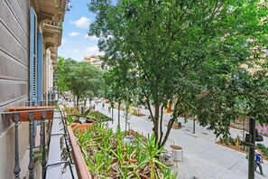 A balcony with potted plants, a view of a city street, and a building facade. - Discover Barcelona from this cozy yet chic 2-bedroom apartment nestled in the vibrant Eixample (Barcelona)
