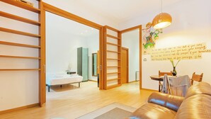 Una sala de estar moderna con un sofá de cuero, estanterías de madera y una zona de comedor con mesa y sillas.
