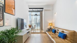 Een moderne woonkamer met een bank, televisie en een eethoek.