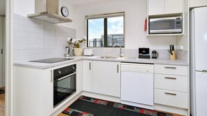 A modern kitchen with white cabinetry, a built-in microwave, a stove, and a dishwasher. - Brand-new, townhouse - walking distance to Westfield Mall (Christchurch)