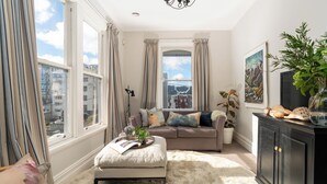 Una sala de estar acogedora con un sofá, un reposapiés y un mueble.