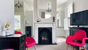 Una sala de estar con chimenea, televisor y sillas rojas.