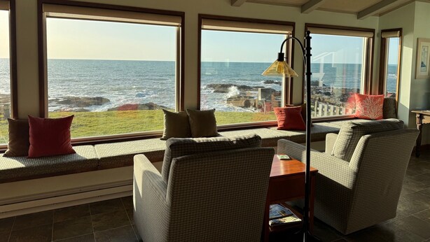A room with large windows overlooking the ocean, wicker furniture, and a lamp. - NEW LISTING! Fantasea! Enjoy dramatic crashing waves, fireplace, dog friendly! (Yachats)