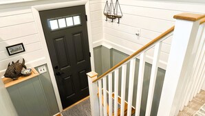 A staircase with a wooden handrail and white balusters, leading to a dark door with a window. - New! Sandy Point-Private beach/Dog Friendly (Eastham)