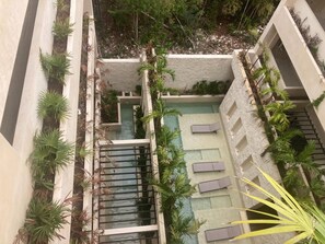 A rooftop pool area with multiple levels, surrounded by plants and built-in seating. - Private Pool - 1 Bedroom Condo - 2 To 4 People (Tulum)