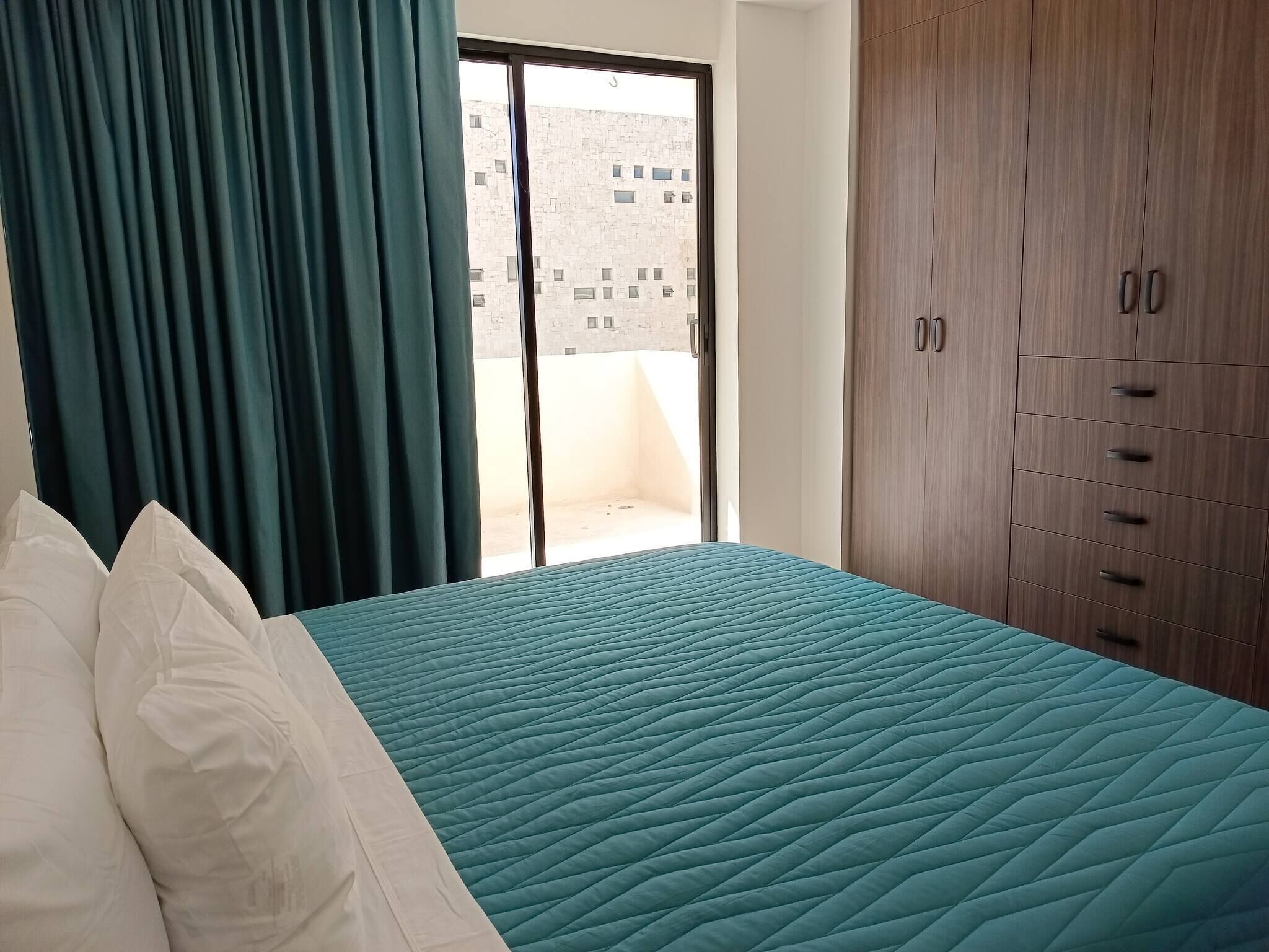 A hotel room with a bed, a wardrobe, and a view of a building outside.