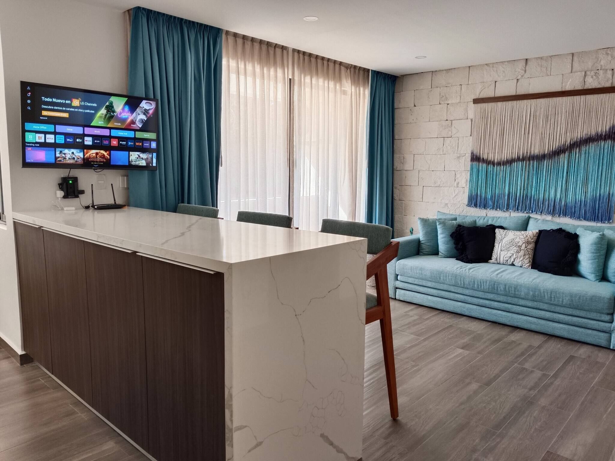A modern living room with a marble island, a flat-screen TV, a blue sofa, and a wall-mounted abstract art piece.