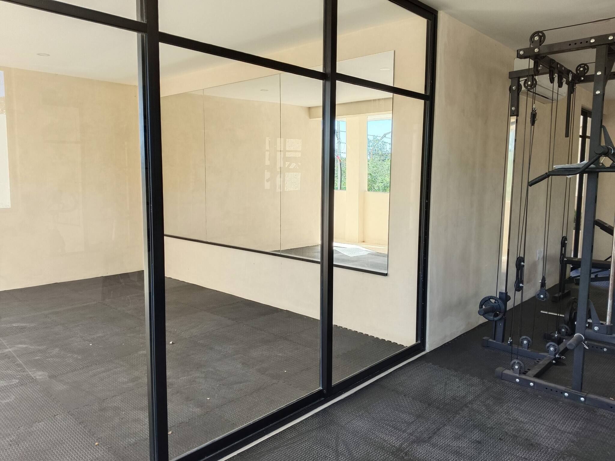 Un gimnasio con paredes de espejo y una zona de levantamiento de pesas.