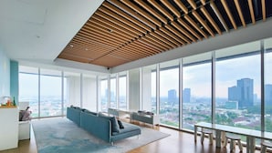 Amplia oficina con diseño moderno, que cuenta con un sofá grande, una zona de comedor y ventanas amplias con vista a la ciudad.