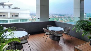 Terraza en la azotea con vistas panorámicas de la ciudad, con una mesa redonda, sillas y plantas en macetas.