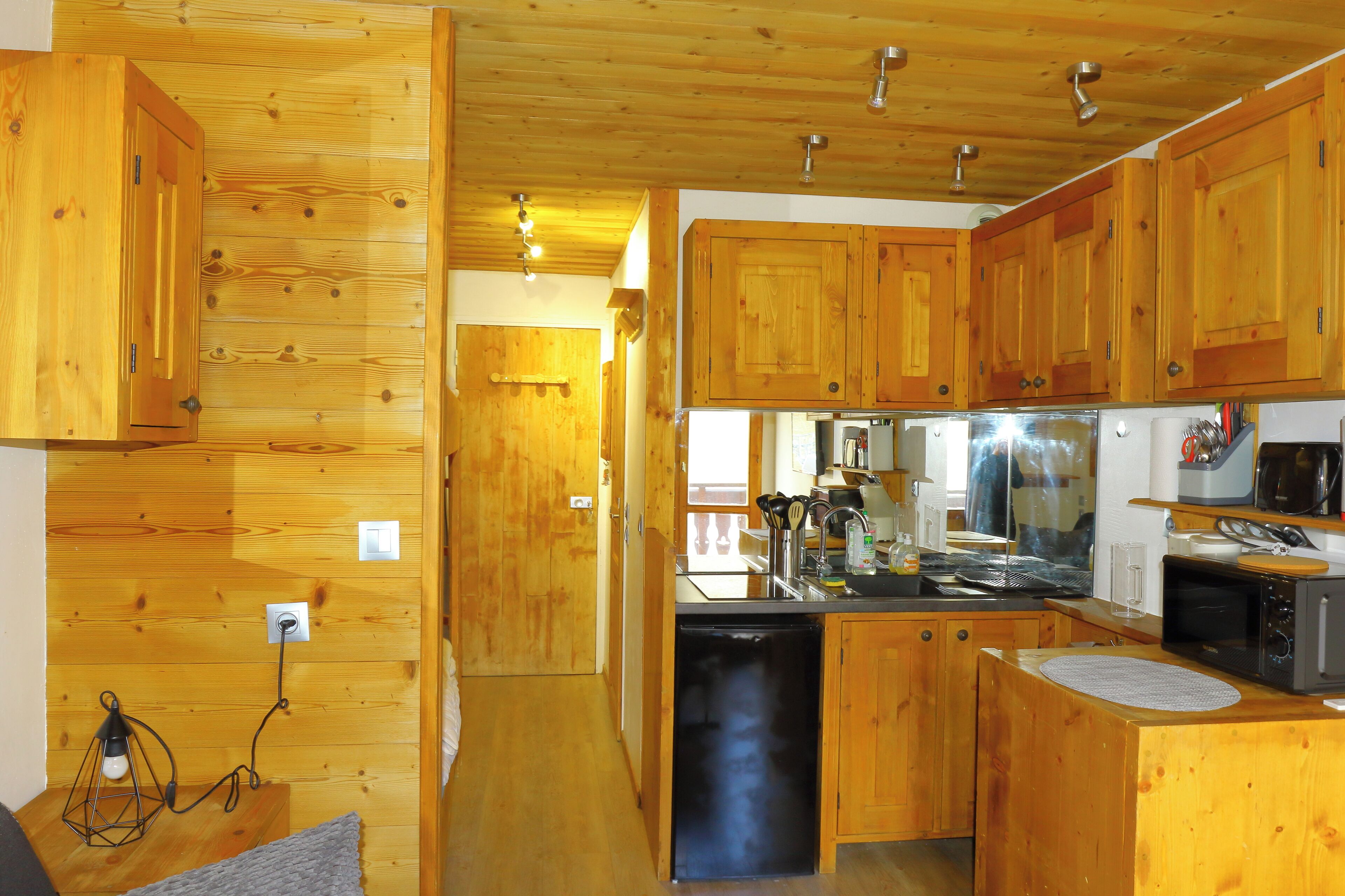 Una cocina compacta con armarios de madera, lavavajillas, microondas y fregadero.