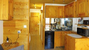 A compact kitchen with wooden cabinetry, a dishwasher, a microwave, and a sink.