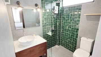 A bathroom with a white sink, a wooden vanity, a glass shower enclosure, and a white toilet.