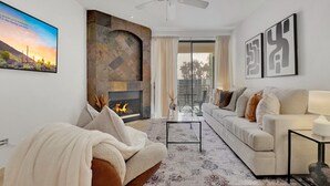 A modern living room with a fireplace, a sofa, a coffee table, and a ceiling fan.