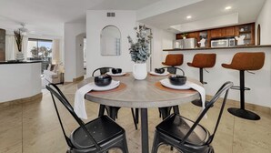 A modern dining area with a round table, black chairs, and a central light fixture.