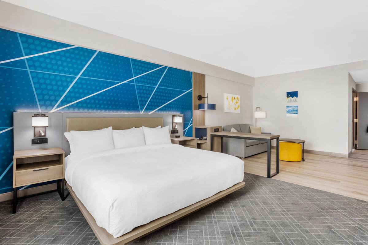 Een moderne hotelkamer met een groot bed, nachtkastjes, een bureau en een stoel.