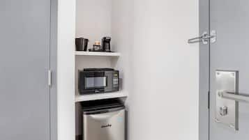 Una cocina compacta con microondas, cafetera y un cubo de basura.