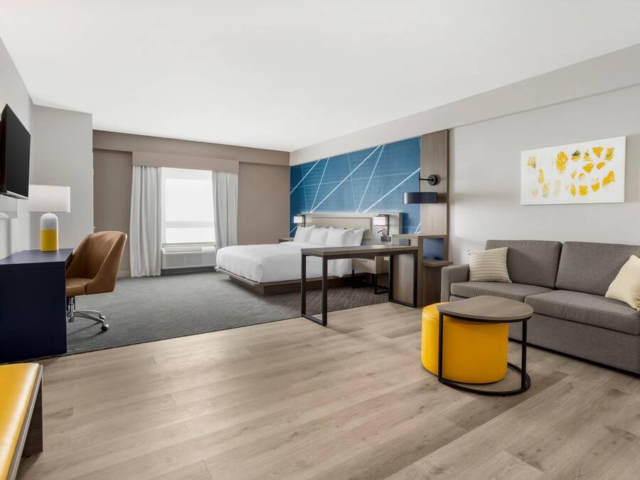 Una habitación de hotel moderna con cama, sofá, escritorio y televisor.