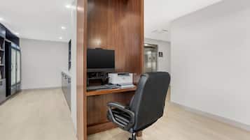 A modern office space with a wooden desk, a black office chair, a flat-screen TV, and a printer.