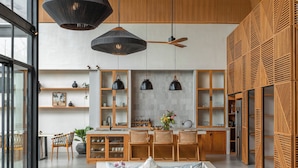 A modern interior with a large seating area, wooden flooring, and a kitchen with open shelving. - Villa Lava (Canggu)
