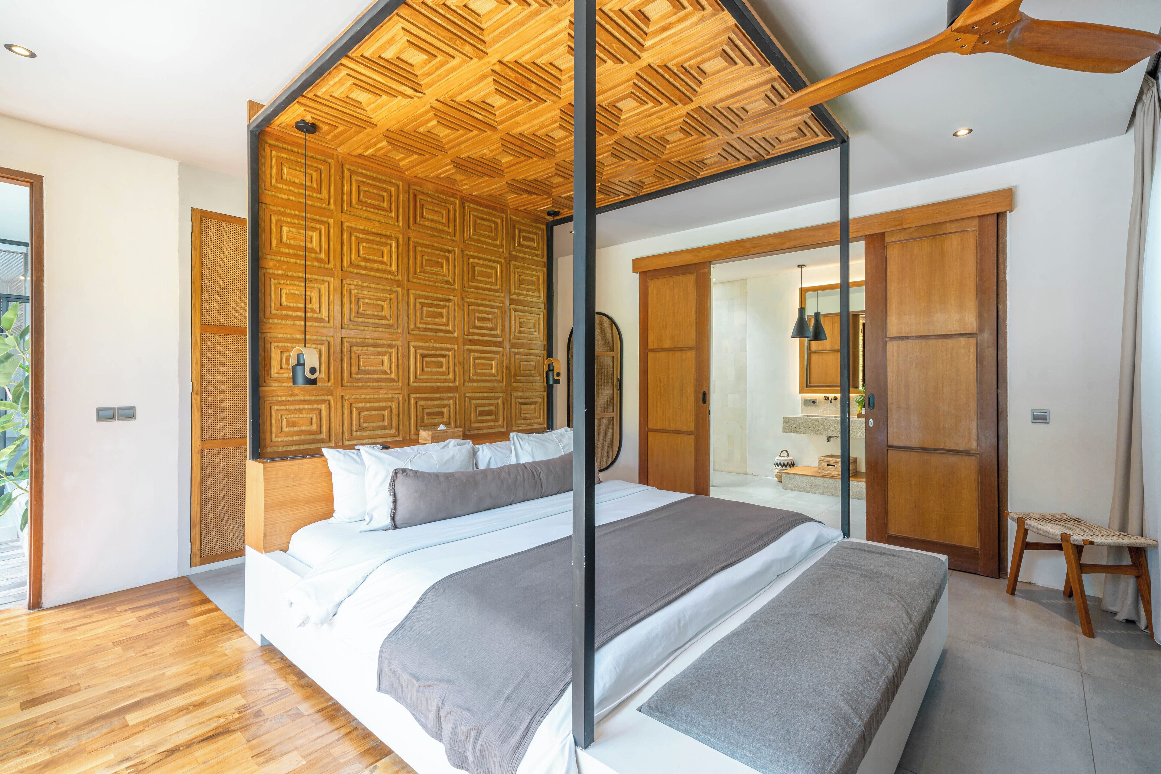 Ein modernes Schlafzimmer mit einem großen Bett, Holzboden und Blick ins Badezimmer.