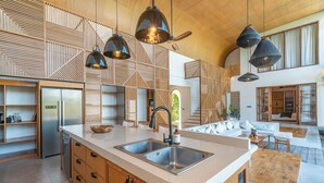 A modern kitchen with a central island, stainless steel appliances, and pendant lighting. - Villa Lava (Canggu)