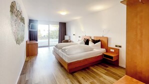 Une chambre d’hôtel avec un grand lit, un plancher en bois, un téléviseur fixé au mur et une vue sur l’extérieur.