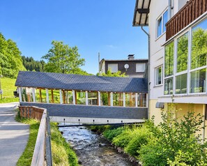 A modern house with a bridge over a stream, surrounded by greenery. - Comfortable and versatile room -perfect for relaxation, work and exchange (Winterberg)