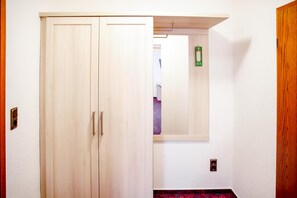 A hallway with a wooden wardrobe, a mirror, and a green sign on the wall.
