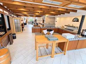 A spacious kitchen with wooden beams, a central island, and a view into the dining area.