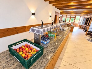A buffet area with a fruit display and beverage dispensers.
