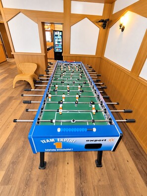 A foosball table with the label 'TEAM EXPERT' in a room with wooden flooring and paneled walls.