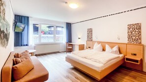 A modern hotel room with a large bed, a desk, and a sofa. - Comfortable and versatile room -perfect for relaxation, work and exchange (Winterberg)