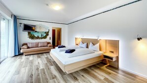 Une chambre d’hôtel moderne avec un grand lit, un canapé, une télévision et un tableau au mur.