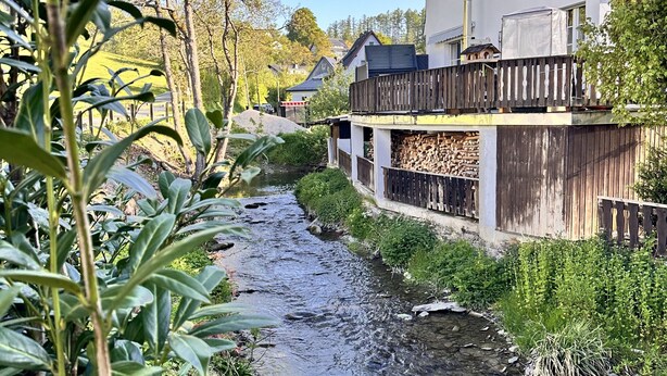 A residential area with a small stream, houses with balconies, and a wooden fence.