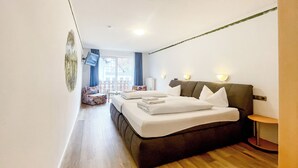 A hotel room with a bed, a small seating area, and a view of the outside. - Comfortable and versatile room -perfect for relaxation, work and exchange (Winterberg)