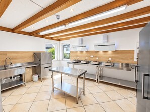 A modern kitchen with stainless steel appliances, a wooden ceiling, and a large window. - Comfortable and versatile room -perfect for relaxation, work and exchange (Winterberg)