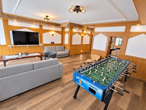 A room with a foosball table, sofas, a TV, and wooden paneling. - Comfortable and versatile room -perfect for relaxation, work and exchange (Winterberg)