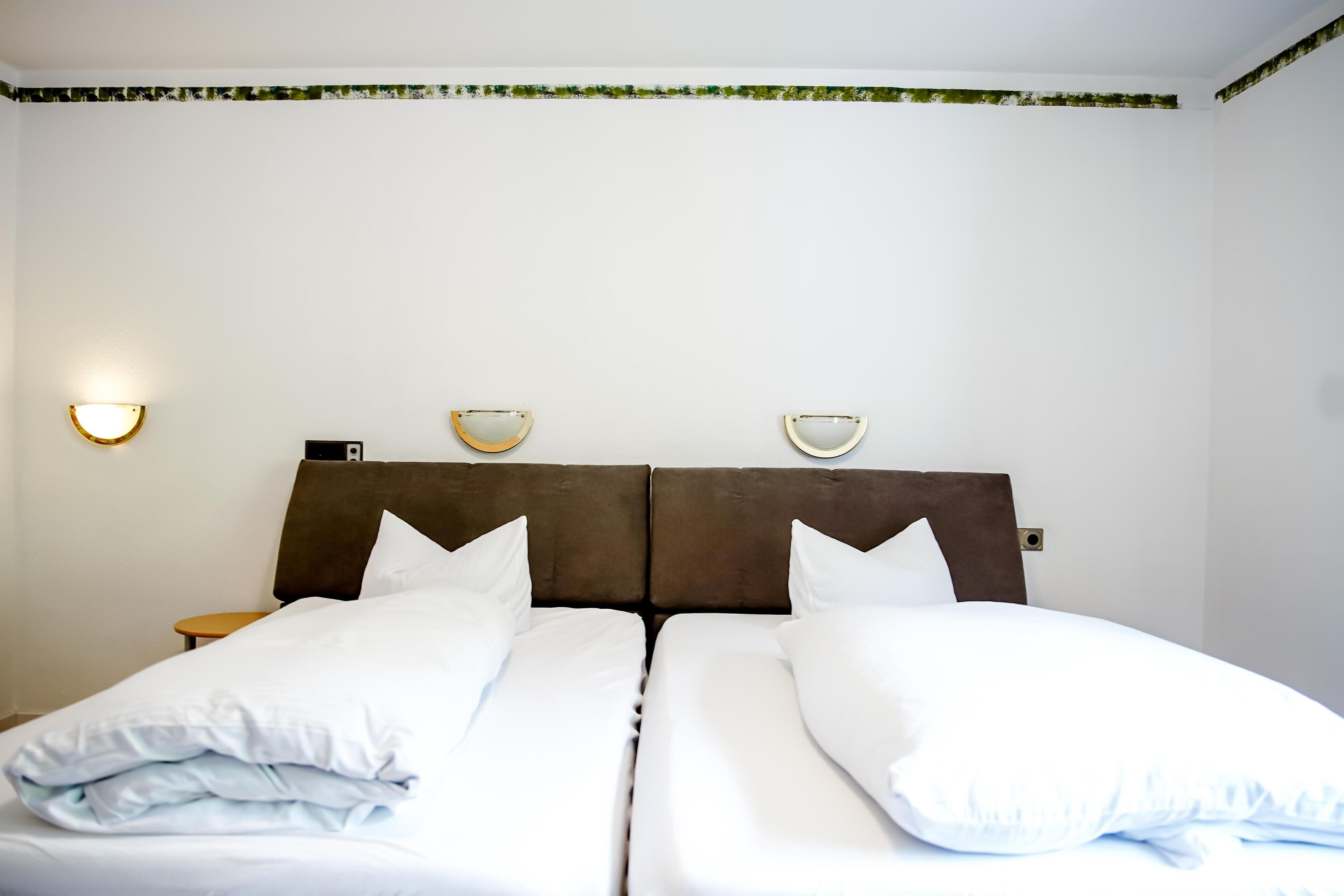 A double bed with white bedding and two wall-mounted lamps.